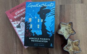 Weihnachtskrimis "Hercule Poirots Weihnachten" und "Geheimnis am Weihnachtsabend" auf dem Boden liegend, daneben zwei sternenförmige Teelichthalter